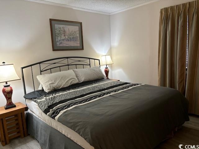 bedroom with hardwood / wood-style flooring, crown molding, and a textured ceiling