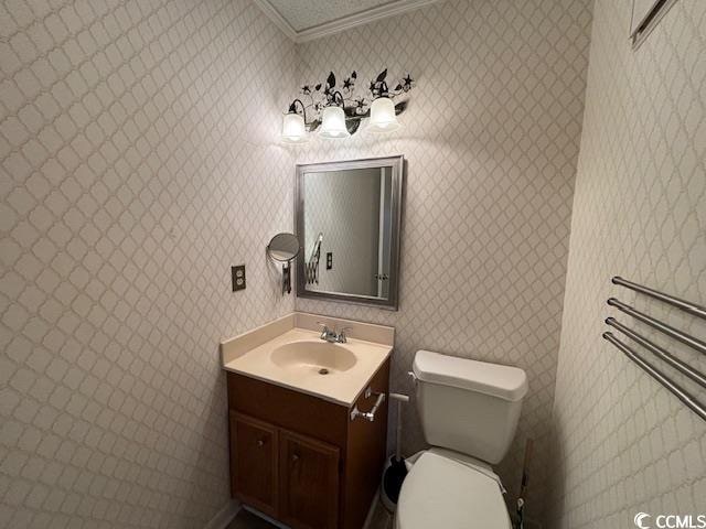 bathroom with vanity, crown molding, and toilet