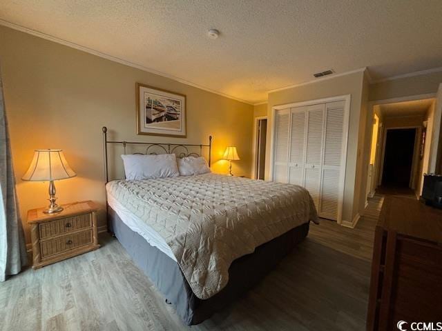 bedroom with ornamental molding, wood-type flooring, a closet, and a textured ceiling