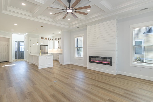 unfurnished living room with a fireplace, coffered ceiling, visible vents, and a healthy amount of sunlight