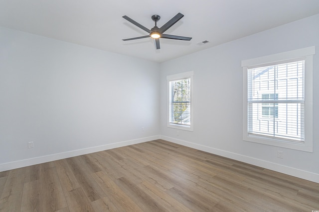 unfurnished room with visible vents, ceiling fan, light wood finished floors, and baseboards