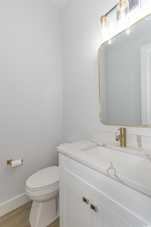 bathroom featuring toilet, baseboards, and vanity