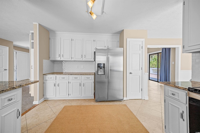 kitchen featuring white cabinets, stainless steel appliances, backsplash, and light tile floors