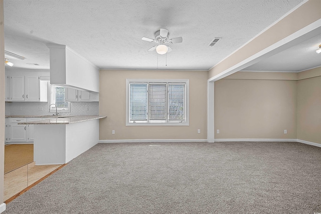 unfurnished living room with a textured ceiling, sink, ceiling fan, and light tile floors