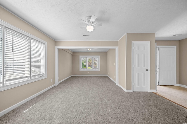 spare room featuring light colored carpet, ceiling fan, and a textured ceiling