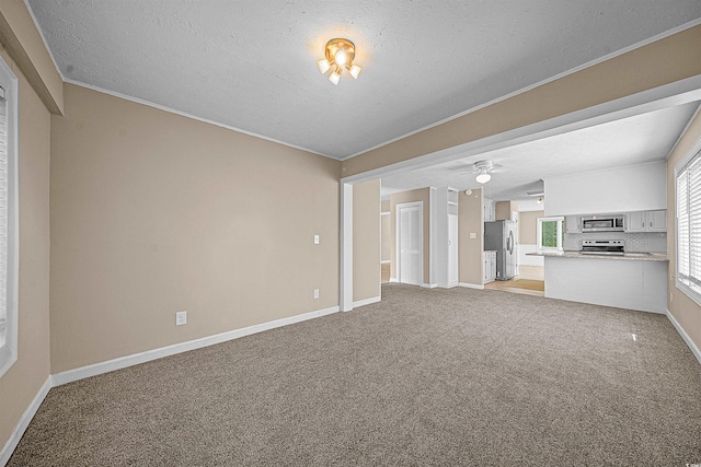 unfurnished living room featuring ornamental molding, ceiling fan, carpet, and a textured ceiling