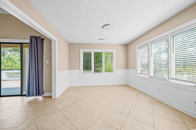 tiled spare room with a textured ceiling