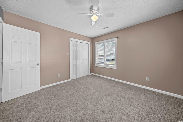 unfurnished bedroom featuring carpet flooring, a closet, ceiling fan, and a textured ceiling