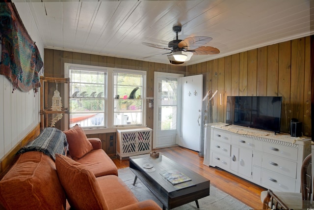 living room with wood walls, ceiling fan, and light hardwood / wood-style flooring