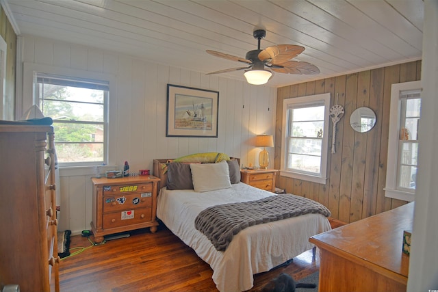 bedroom featuring ceiling fan, wood walls, and dark wood-type flooring