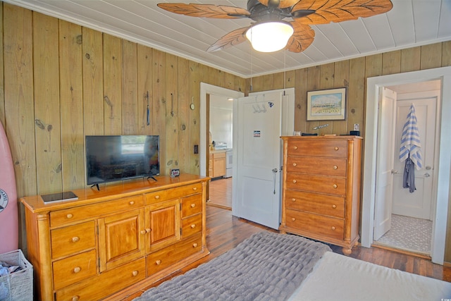 bedroom featuring wood walls, wood-type flooring, and ceiling fan