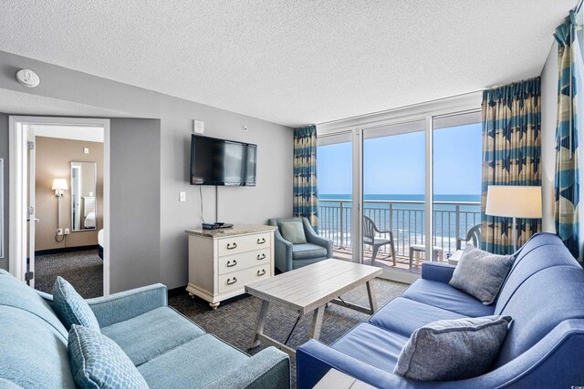 living room featuring a water view, a textured ceiling, dark carpet, and plenty of natural light