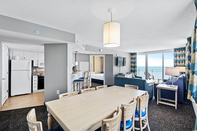 dining area with a water view, a textured ceiling, light colored carpet, and floor to ceiling windows