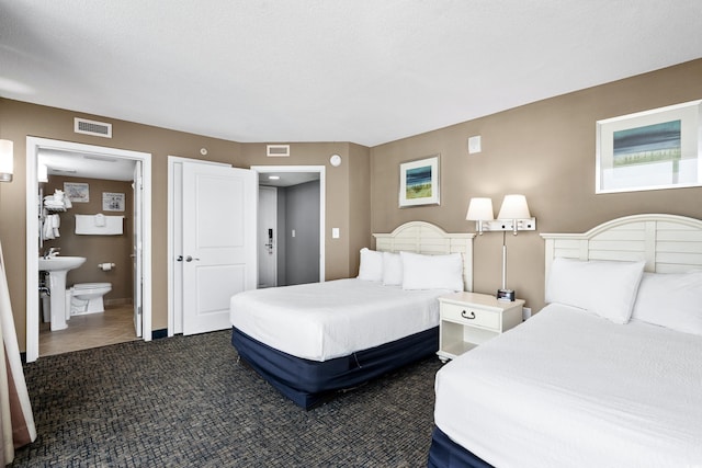 bedroom featuring ensuite bath and dark tile floors