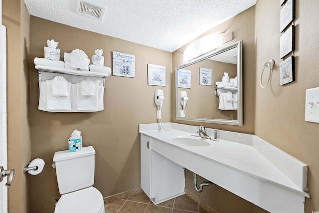 bathroom with a textured ceiling, vanity, toilet, and tile flooring