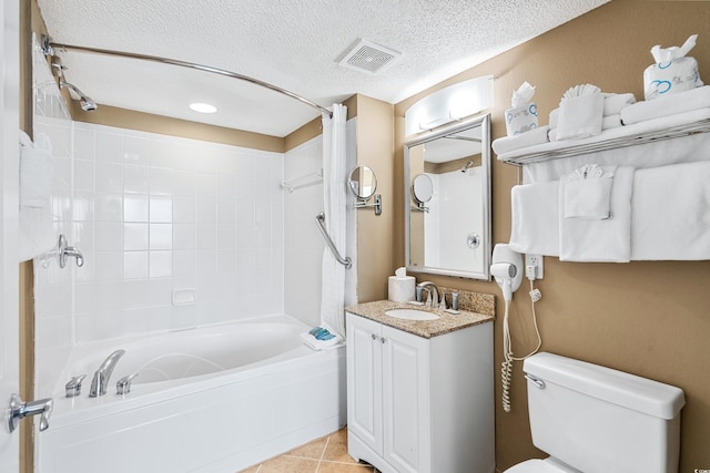 full bathroom with tiled shower / bath, vanity, tile flooring, toilet, and a textured ceiling