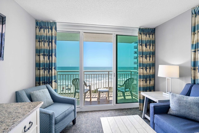 living room with carpet, a water view, and a textured ceiling