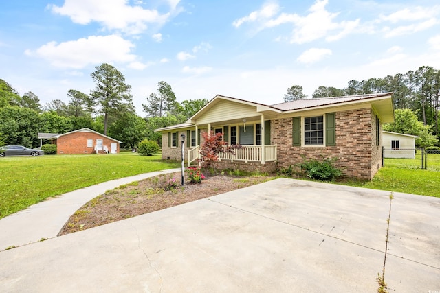 ranch-style home featuring covered porch and a front yard