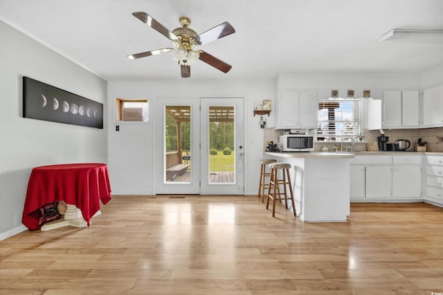 kitchen featuring plenty of natural light, a kitchen breakfast bar, kitchen peninsula, and white cabinetry