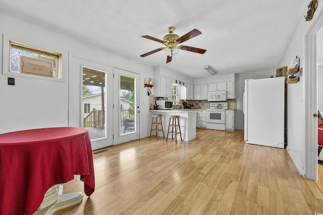 interior space with a textured ceiling, ceiling fan, and light hardwood / wood-style floors