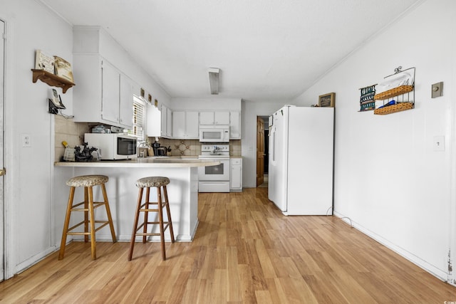 kitchen featuring white cabinetry, light hardwood / wood-style flooring, and white appliances