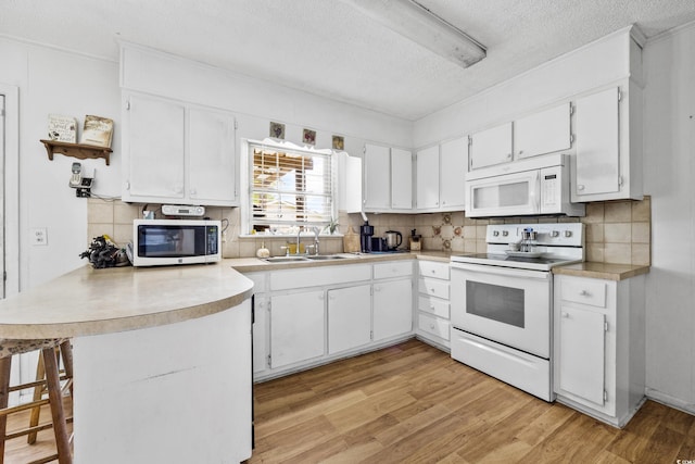 kitchen featuring sink, light hardwood / wood-style floors, white appliances, white cabinetry, and kitchen peninsula