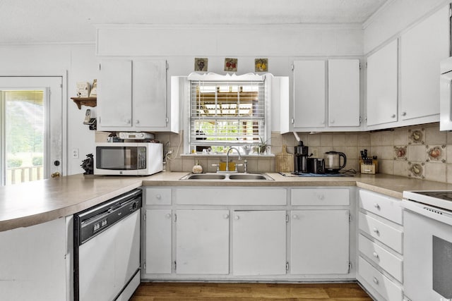 kitchen featuring sink, white appliances, white cabinetry, and a wealth of natural light