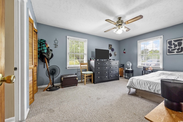 carpeted bedroom featuring a textured ceiling, ceiling fan, and multiple windows