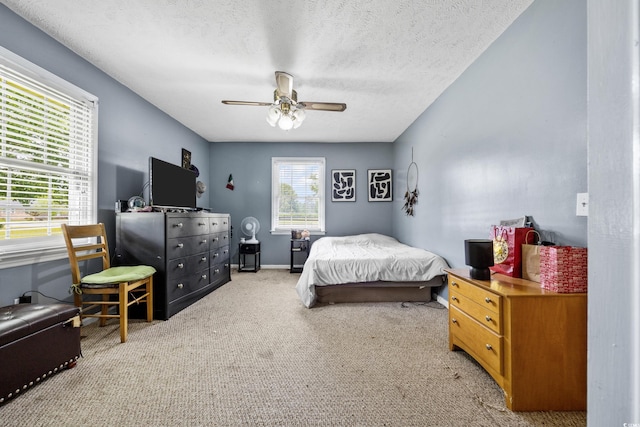 carpeted bedroom featuring ceiling fan and a textured ceiling