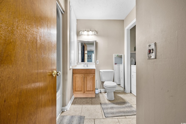 bathroom featuring toilet, tile floors, vanity, and a textured ceiling