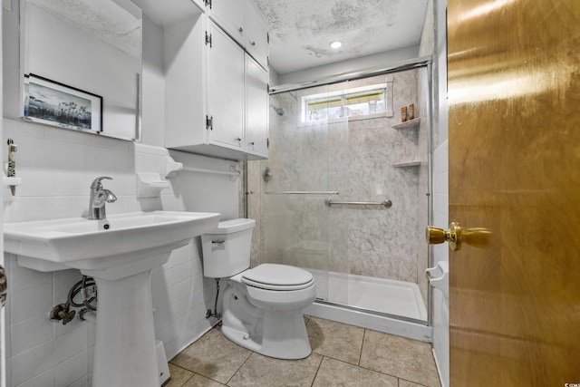 bathroom featuring tile flooring, a shower, toilet, and a textured ceiling