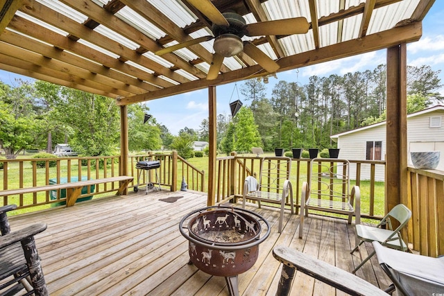 wooden terrace with an outdoor fire pit, a lawn, and ceiling fan