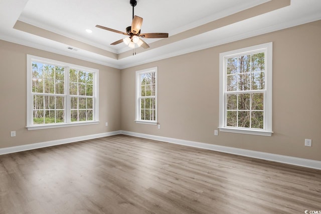 spare room with plenty of natural light, ceiling fan, hardwood / wood-style flooring, and a tray ceiling