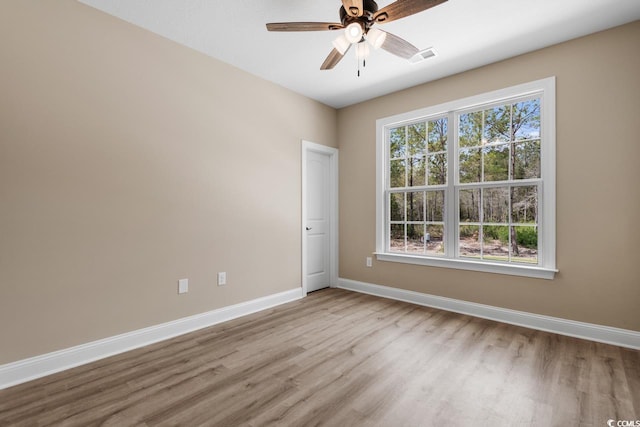 spare room with plenty of natural light, wood-type flooring, and ceiling fan