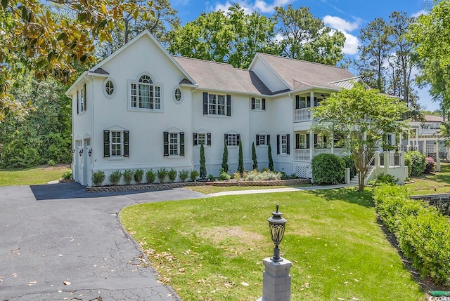 view of front of property featuring a balcony and a front yard