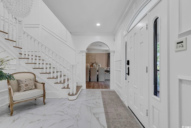 foyer entrance featuring crown molding and decorative columns