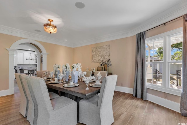 dining space with decorative columns, light hardwood / wood-style floors, and ornamental molding