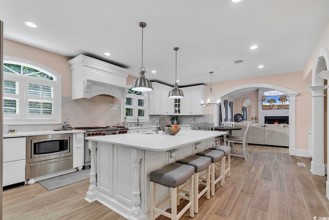 kitchen featuring white cabinetry, pendant lighting, appliances with stainless steel finishes, and light hardwood / wood-style floors