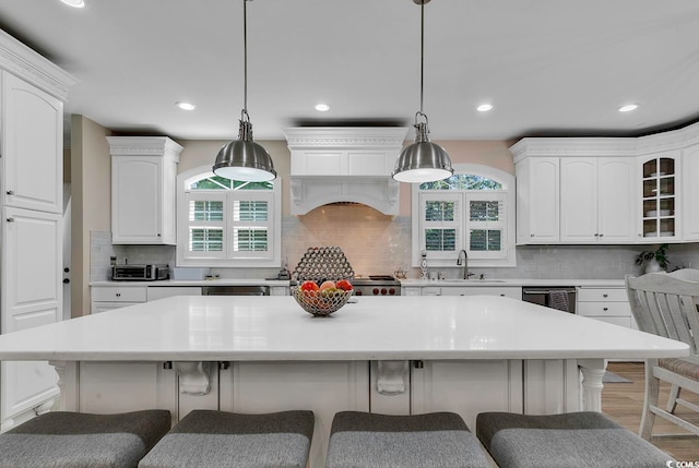 kitchen featuring a large island, white cabinets, pendant lighting, and sink