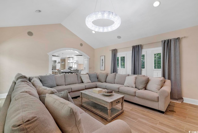 living room featuring light wood-type flooring, vaulted ceiling, and a notable chandelier