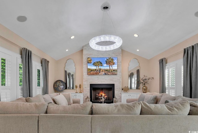 living room featuring a fireplace, a healthy amount of sunlight, vaulted ceiling, and an inviting chandelier