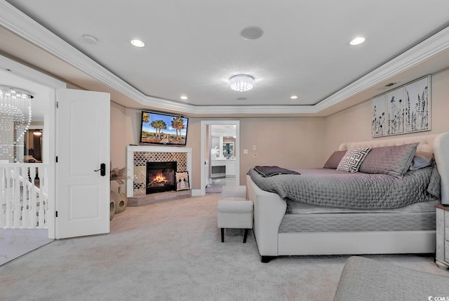 carpeted bedroom with a tiled fireplace, crown molding, and a tray ceiling