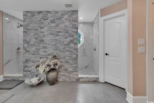 bathroom featuring tile patterned flooring and tiled shower