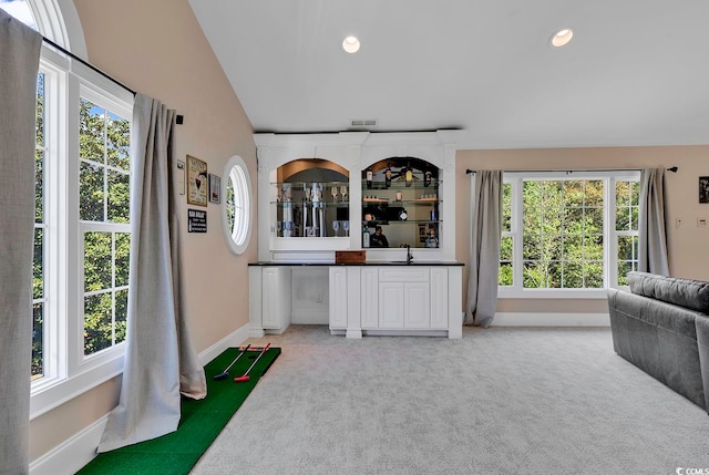 carpeted living room featuring a wealth of natural light, sink, and vaulted ceiling