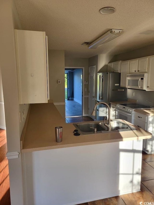 kitchen with light tile patterned flooring, white cabinets, white appliances, sink, and kitchen peninsula