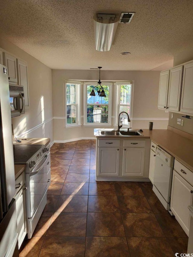 kitchen featuring appliances with stainless steel finishes, kitchen peninsula, dark tile patterned floors, and white cabinetry