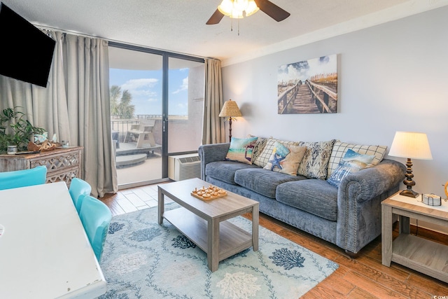 living room featuring expansive windows, ceiling fan, hardwood / wood-style flooring, and a textured ceiling