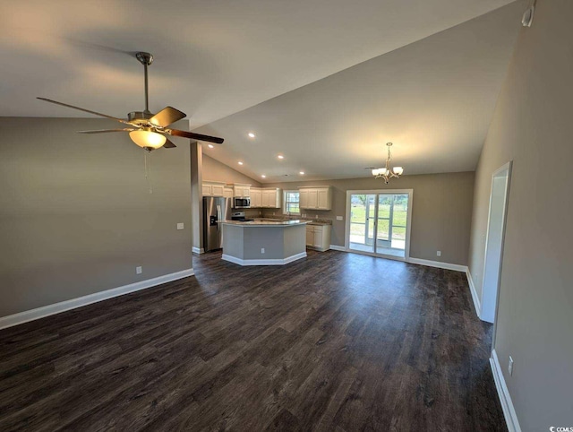 unfurnished living room featuring ceiling fan with notable chandelier, lofted ceiling, baseboards, and dark wood-style flooring