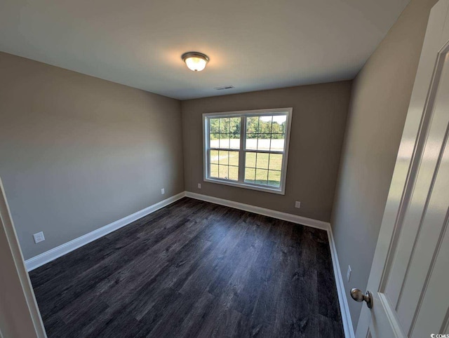 unfurnished room with visible vents, baseboards, and dark wood-type flooring