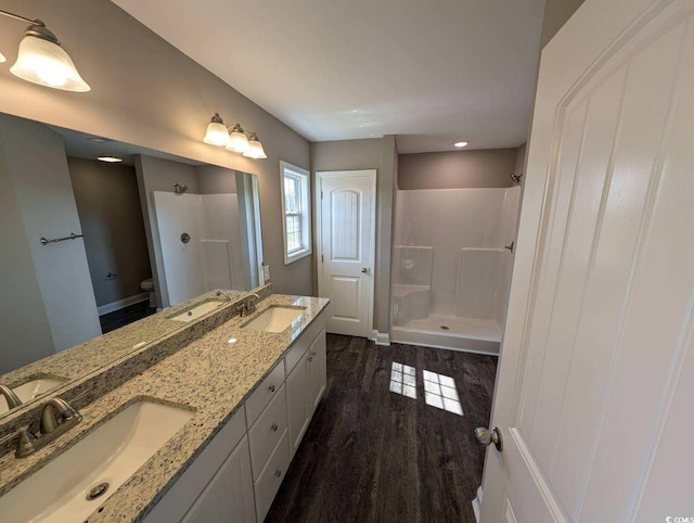 full bathroom with toilet, wood finished floors, walk in shower, and a sink